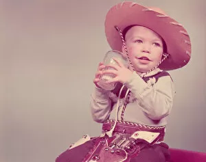 Liquid Gallery: Toddler boy dressed as cowboy, drinking glass of milk. (Photo by H