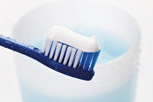 Liquid Gallery: Toothbrush with toothpaste in front of a toothbrush tumbler with mouthwash