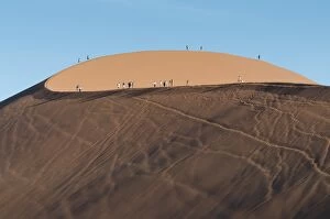 Tourists walking on the top of the famous Dune 45 sand dune. Sossuvlei, Namibia