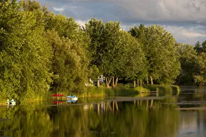 Trees and boats on Yamaska River in evening light with threatening clouds, Waterloo, Eastern Townships, Quebec Province