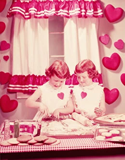 Extreme Close Up Gallery: Twin girls in kitchen, baking Valentine cookies