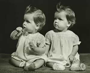 Twin Gallery: Twin sisters (9-12 months)sitting on blanket, (B&W), portrait