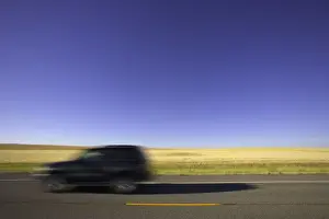 USA, Montana, SUV on highway beside wheatfield (blurred motion)