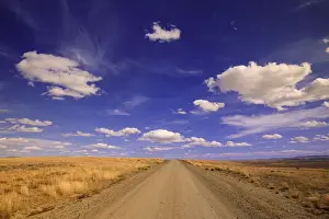 Absence Prints: USA, Wyoming, Red Desert, cumulus clouds over gravel range road