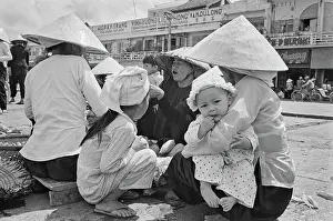 Prints of Vietnamese women and their children, some wearing traditional non la hats on an embankment of the Saigon River as it flows through Saigon, Vietnam, 30th August 1965 Vietnam Prints: Vietnamese Women & Children In Saigon