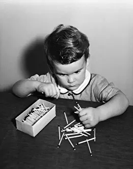 Match Prints: Vintage photograph showing boy (4-5) playing with matches