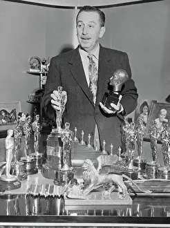 Walt Disney Standing over Table of Trophies