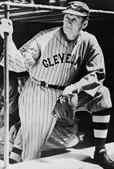 Prints of circa 1920: A portrait of baseball pitcher Walter Johnson, wearing a Cleveland uniform and a baseball glove, leans on his knee, while gripping a bar inside a dugout MLB Legends Art Prints: Top 10 Greatest Baseball Players of All Time: Walter Johnson