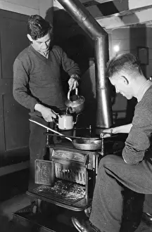 Prints of February 1941: Two watchmen off duty brewing up tea on a stove. Original Publication: Picture Post - 1021 - Balloons In The Estuary - pub Discover the Vision of Haywood Magee – A Master of Mid-Century British Life: Watchmen Make Tea