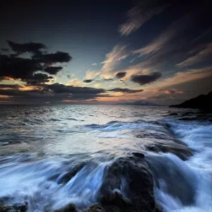 Water flowing over rocks on sea at sunset