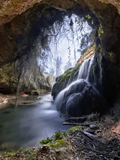 Waterfall view from inside a cave in a forest