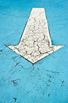 White arrow on blue concrete with cracks
