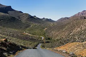 Vast Prints: The winding road climbing up the remote and rugged wilderness area of the Cederberg mountains in the distance