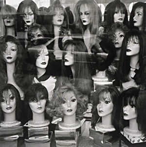 Window display of mannequin heads wearing assorted wigs