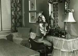 Blonde Hair Prints: Woman applying lipstick at vanity table, (B&W)