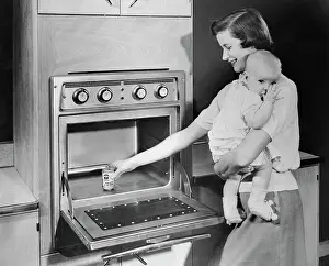 Convenience Prints: Woman with Baby Heating Up Food in New Oven