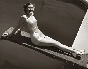 Woman in bathing suit sitting on diving board