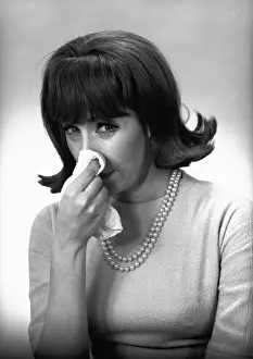 Woman blowing nose in studio, (B&W)