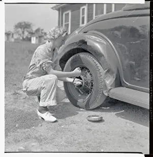Woman Changing Tire at Gas Station