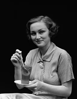 Liquid Gallery: Woman in checked dress, stirring a glass of iced tea, portrait