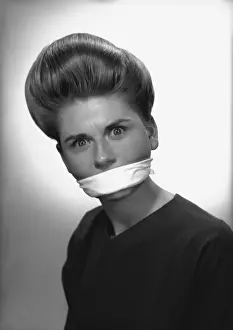 Woman with covered mouth in studio, (B&W), portrait