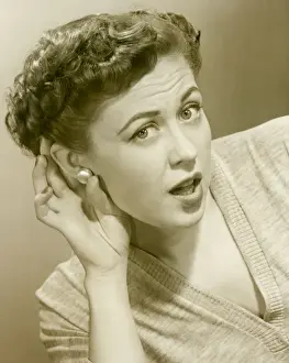 Woman cupping hand to ear, portrait