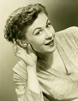 Raised Eyebrow Prints: Woman cupping hand to ear in studio, (B&W), close-up, portrait