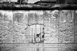 Berlin Wall (Antifascistischer Schutzwall) Collection: Woman cycling by a part of the Berlin Wall