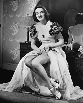 Femininity Prints: Woman in evening gown putting on stockings at vanity table (B&W), portrait