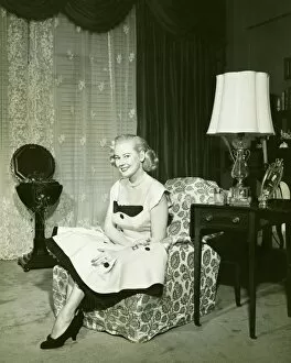 35 39 Years Collection: Woman in fashionable dress sitting on armchair in living room, (B&W), portrait