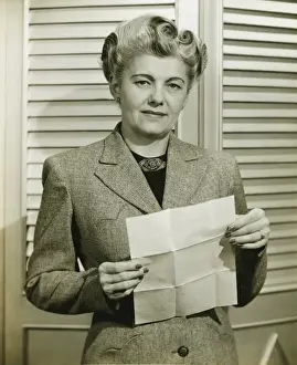 40 49 Years Prints: Woman in fashionable suit holding sheet of paper, indoors, (B&W)