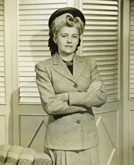 Woman in fashionable suit standing indoors, (B&W)
