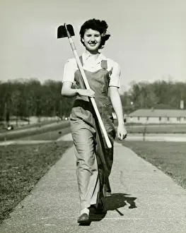 Woman with hoe walking on path, (B&W), portrait