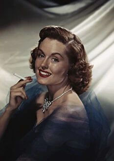 Images Dated 18th July 2011: Woman holding cigarette, smiling, portrait