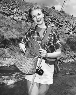 Woman holding creel and fishing rod