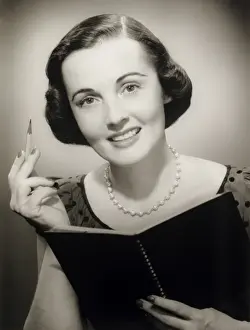 Eyewear Prints: Woman holding pencil and notebook, posing in studio, (B&W), (Close-up), (Portrait)