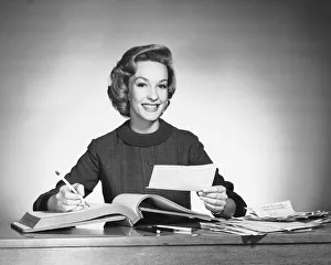 Dedication Gallery: Woman holding pencil and paper, open book in front of her