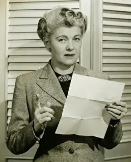 50 59 Years Prints: Woman holding sheet of paper, pointing, (B&W), portrait