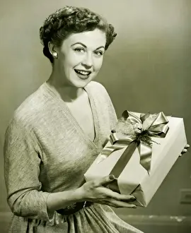35 40 Years Prints: Woman holding wrapped gift in studio, (B&W), portrait