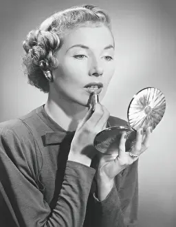 Easy Retouch Prints: Woman looking at hand mirror, applying lipstick, (B&W)