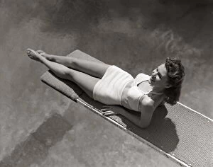 Images Dated 11th October 2005: Woman Lying On Diving Board Over Pool Sunbathing Two Piece Bathing Suit Summer