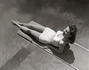Sunbathing Prints: Woman Lying On Diving Board Over Pool Sunbathing Two Piece Bathing Suit Summer