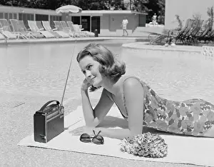 Radio Prints: Woman lying on towel poolside listening to radio with antenna up