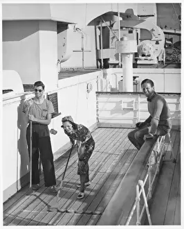 Woman and two men on cruiser deck, (B&W), elevated view