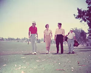 Woman and two men golfing with caddy