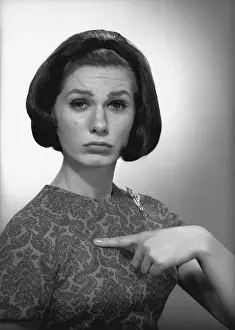 Woman pointing on herself in studio, (B&W), portrait