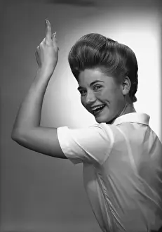 Woman pointing up in studio, (B&W), portrait