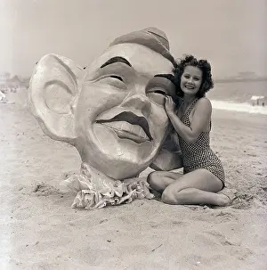 Woman Poses with Huge Mask on Beach
