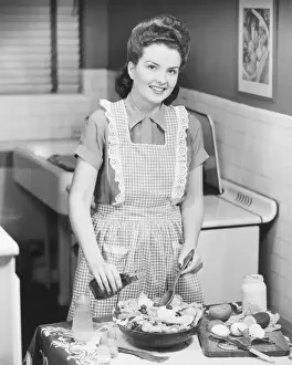 Woman preparing salad in kitchen, (B&W)