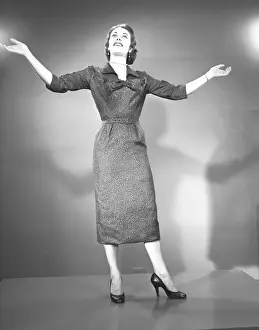 Woman raising hands in studio, (B&W)